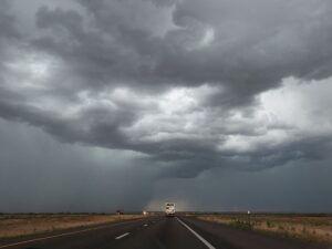 Storm overhead with a ceiling of very dark, foreboding clouds and what appears to be a small funnel over the freeway.